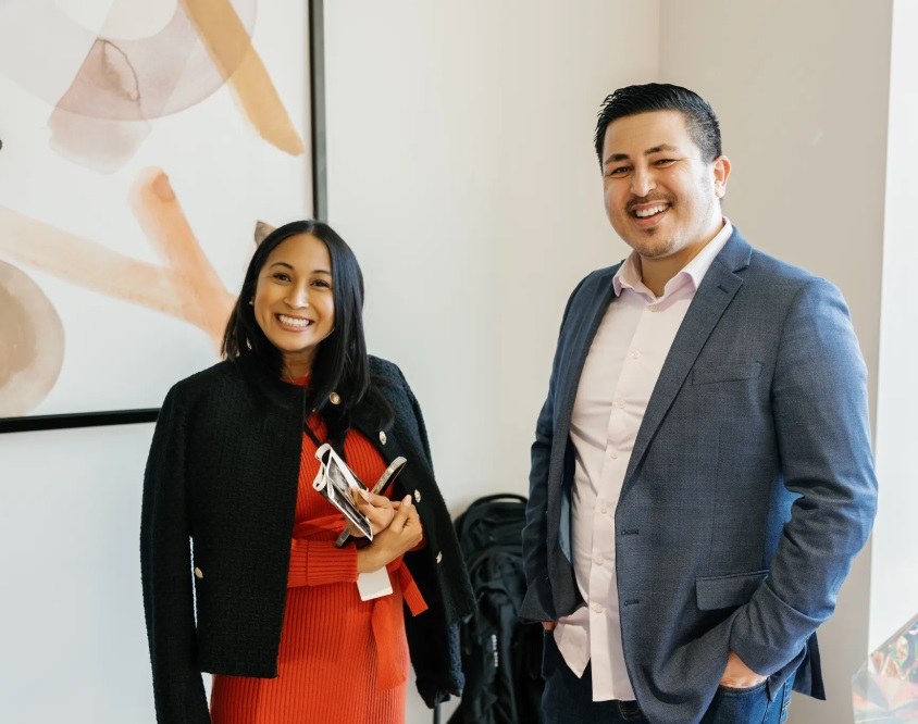 Woman and man in casual business attire smiling.